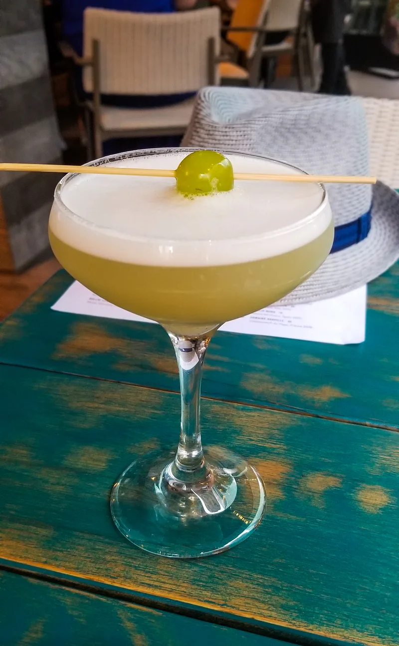 Copa de pisco sour con su capa de espuma y gotas de amargo